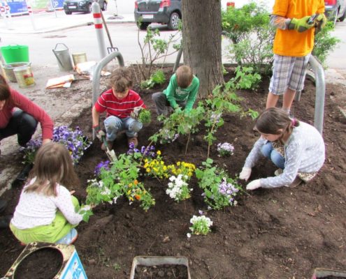 Kinder bepflanzen gemeinsam eine Baumscheibe in der Stadt