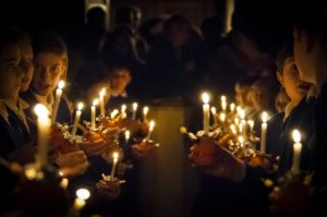 Kinder mit Kerzen in dunkler Kirche
