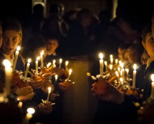 Kinder mit Kerzen in dunkler Kirche